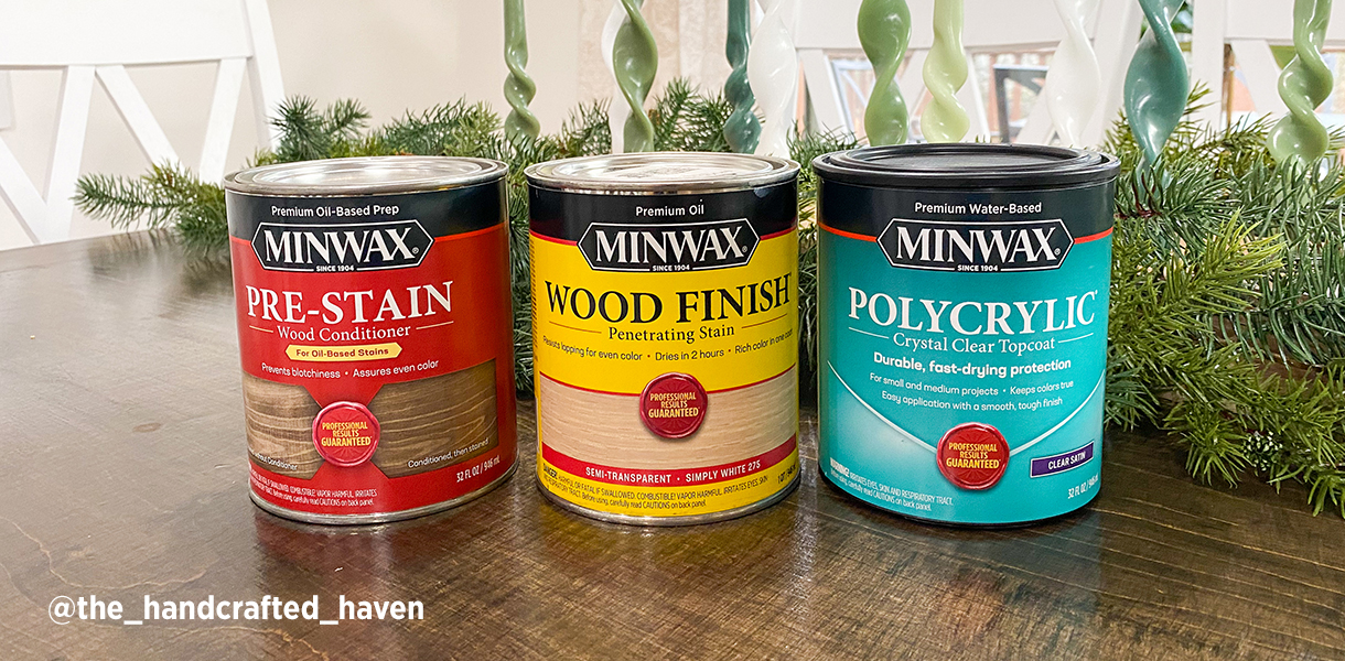 One quart cans of Minwax Pre-Stain Conditioner, Wood Finish and Polycrylic Finish on a wood table with a holiday centerpiece.