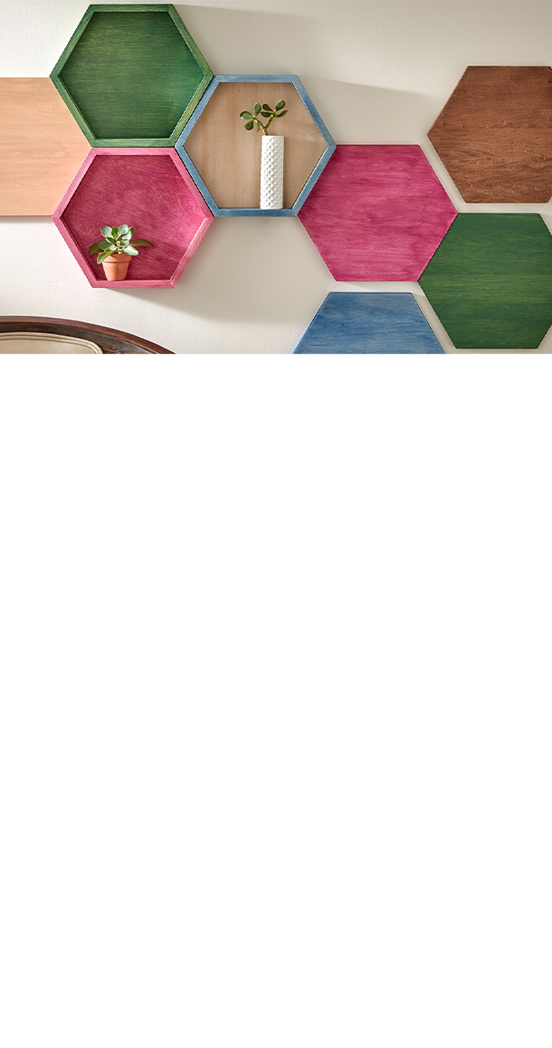 Large, connected and colorful hexagonal wood wall art, interspersed with hexagonal shelving, mounted to a living room wall. 