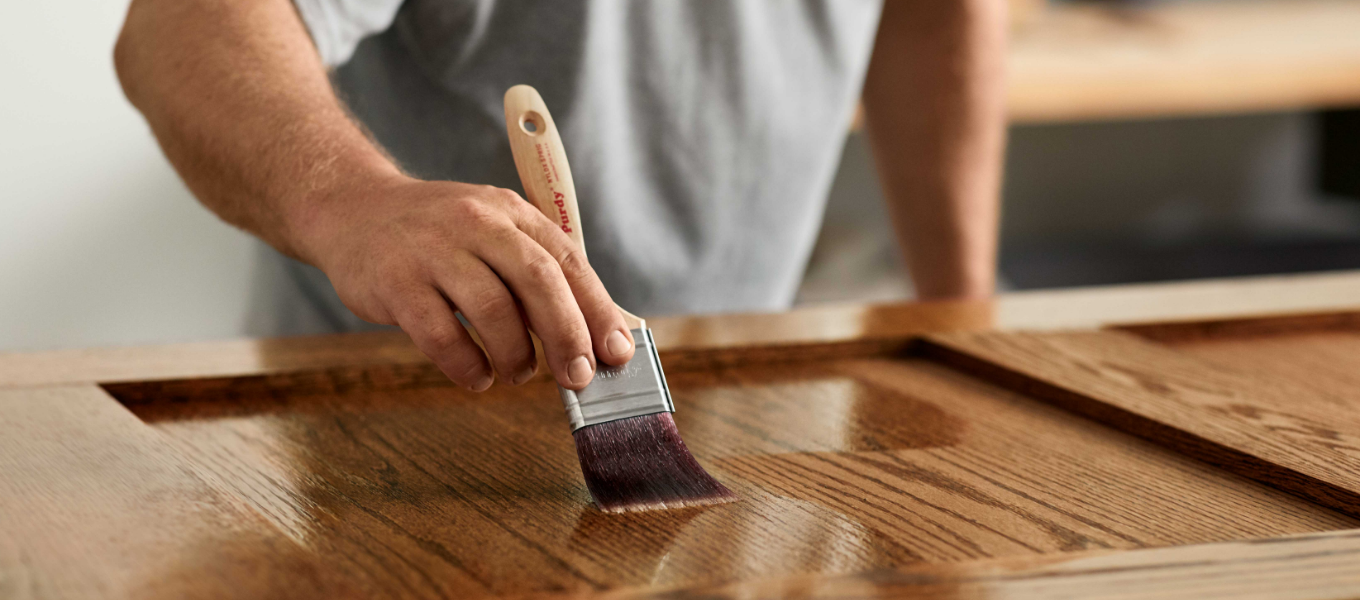 A pro painter applies finish to a piece of wood furniture